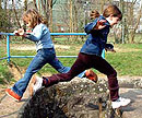 Zwei Kinder aus dem Gartenhort Darmstadt springen über den Darmbach 
